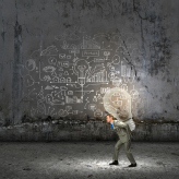 Young businessman carrying light bulb on back