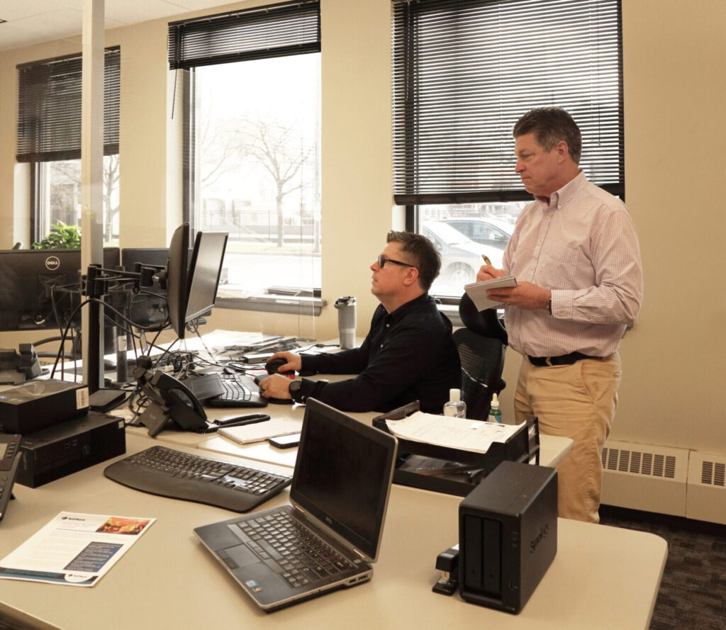 Two IT team employees discussing work and looking at a computer