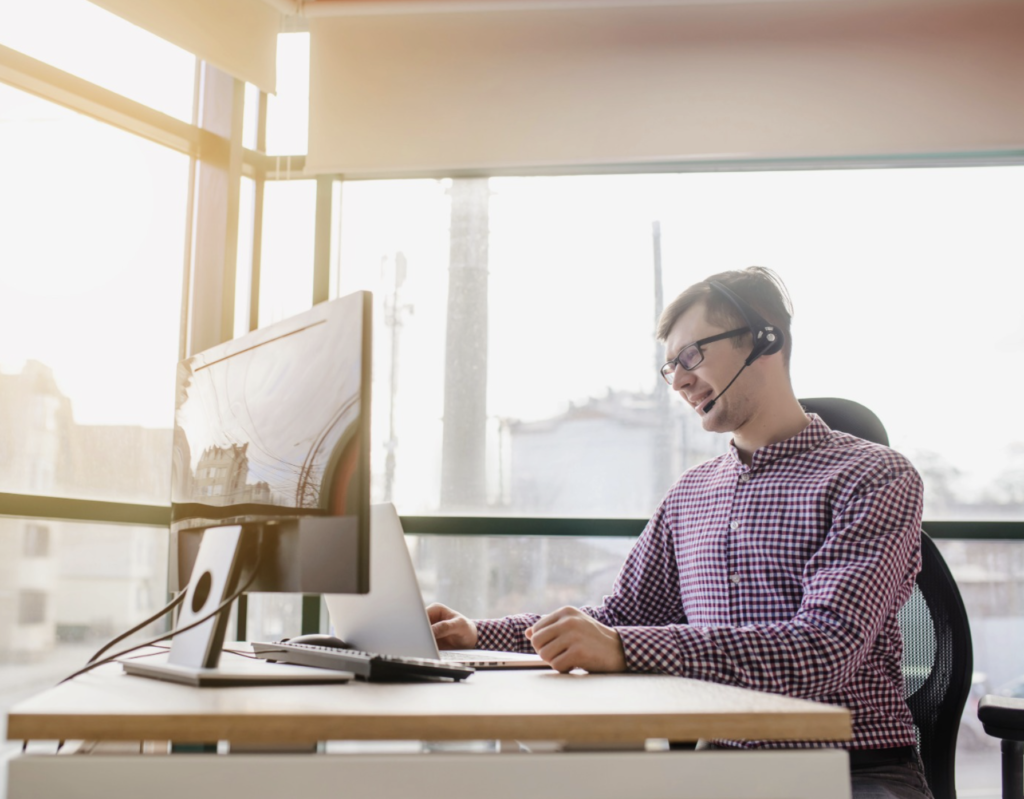 Managed IT services professional providing support with headset and computer in modern office.