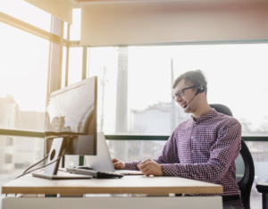 Managed IT services professional providing support with headset and computer in modern office.