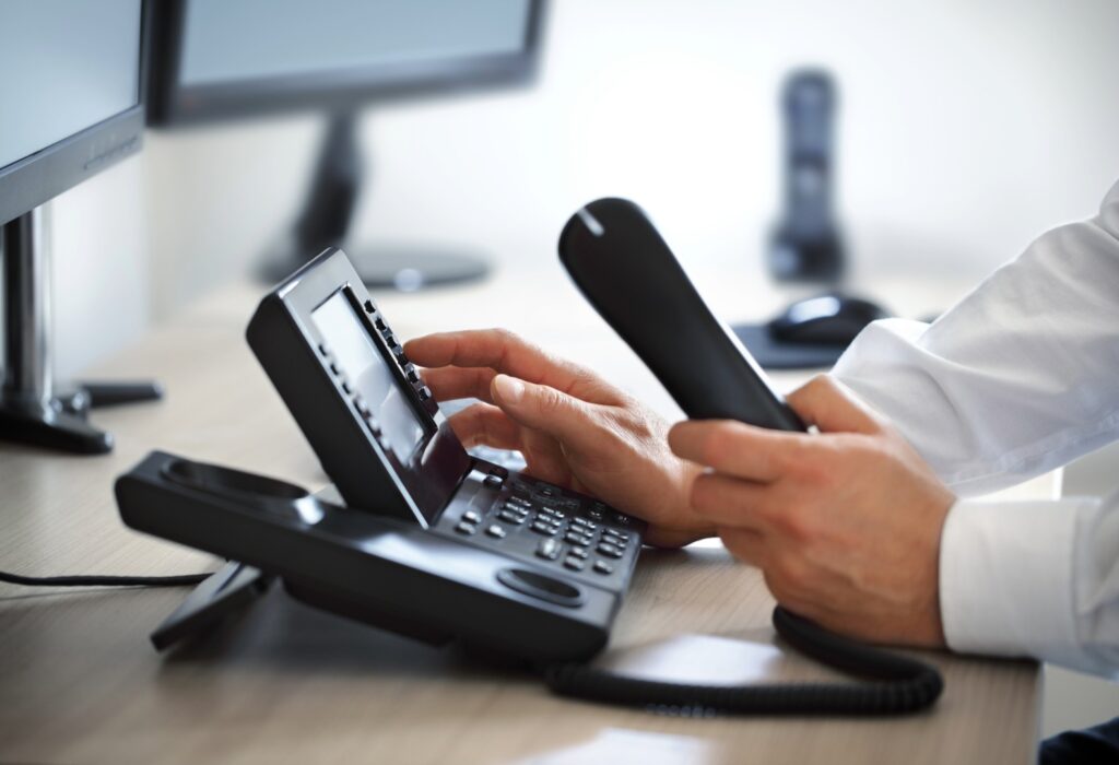 A business professional using a VoIP phone system in an office for business communication.