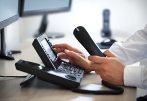 A business professional using a VoIP phone system in an office for business communication.