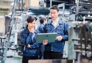 Manufacturing workers using a tablet to manage industrial IT systems and production equipment in their facility.